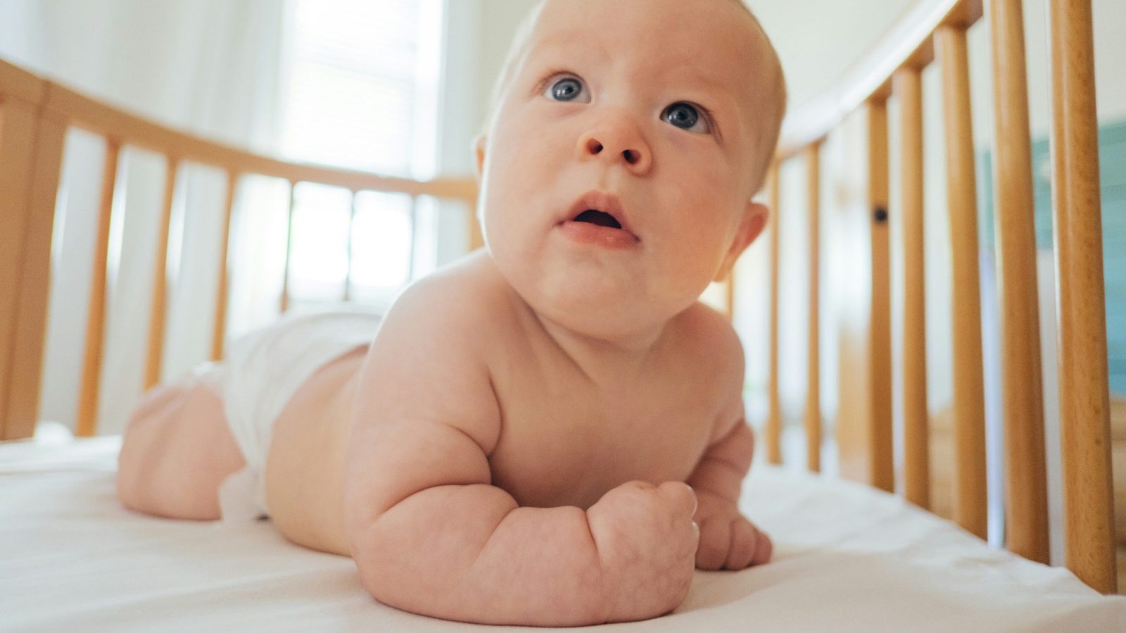 gros plan sur un bébé allongé sur le ventre dans son lit à barreau