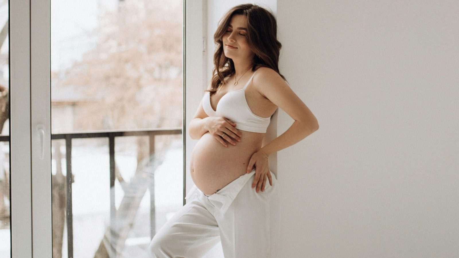 femme enceinte en soutien gorge qui sourit et se tient le ventre