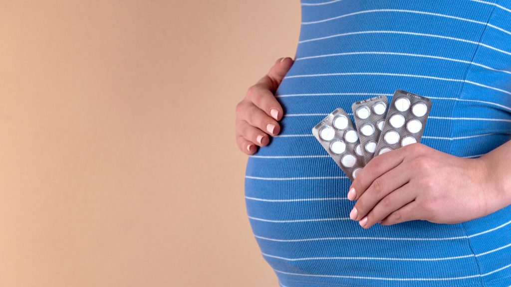 femme enceinte avec des compléments alimentaires dans sa main