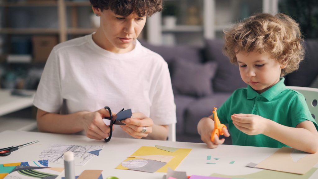 parent avec son enfant à table qui manipulent des ciseaux