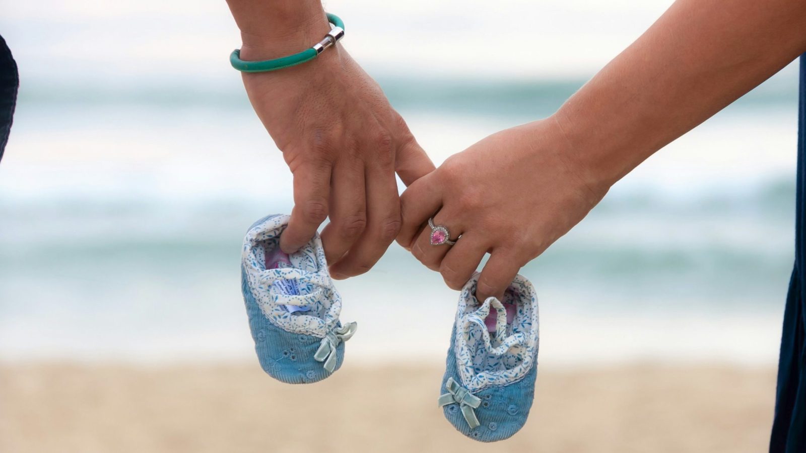 couple qui se tient la main et deux petits chaussons d'enfant